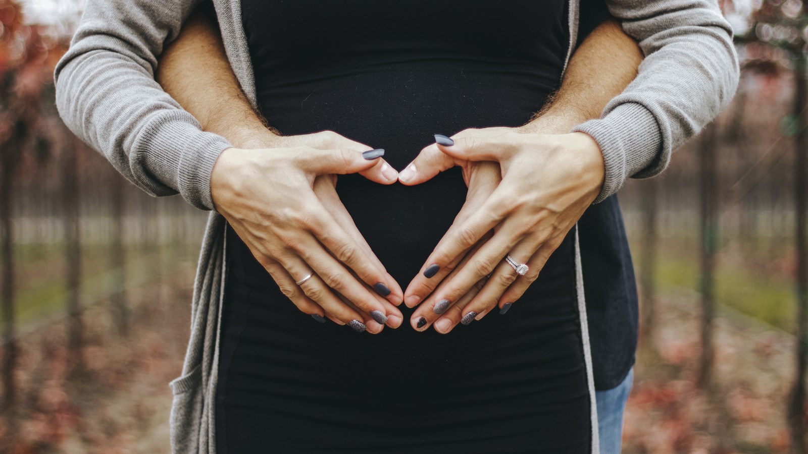En bild på händer som bildar ett hjärta framför en gravid mage.